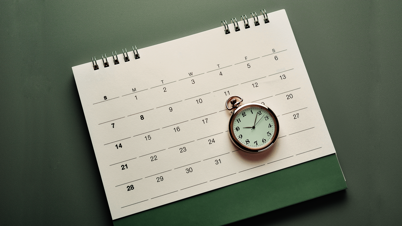 Ein grüner Terminkalender auf dem eine Taschenuhr liegt.