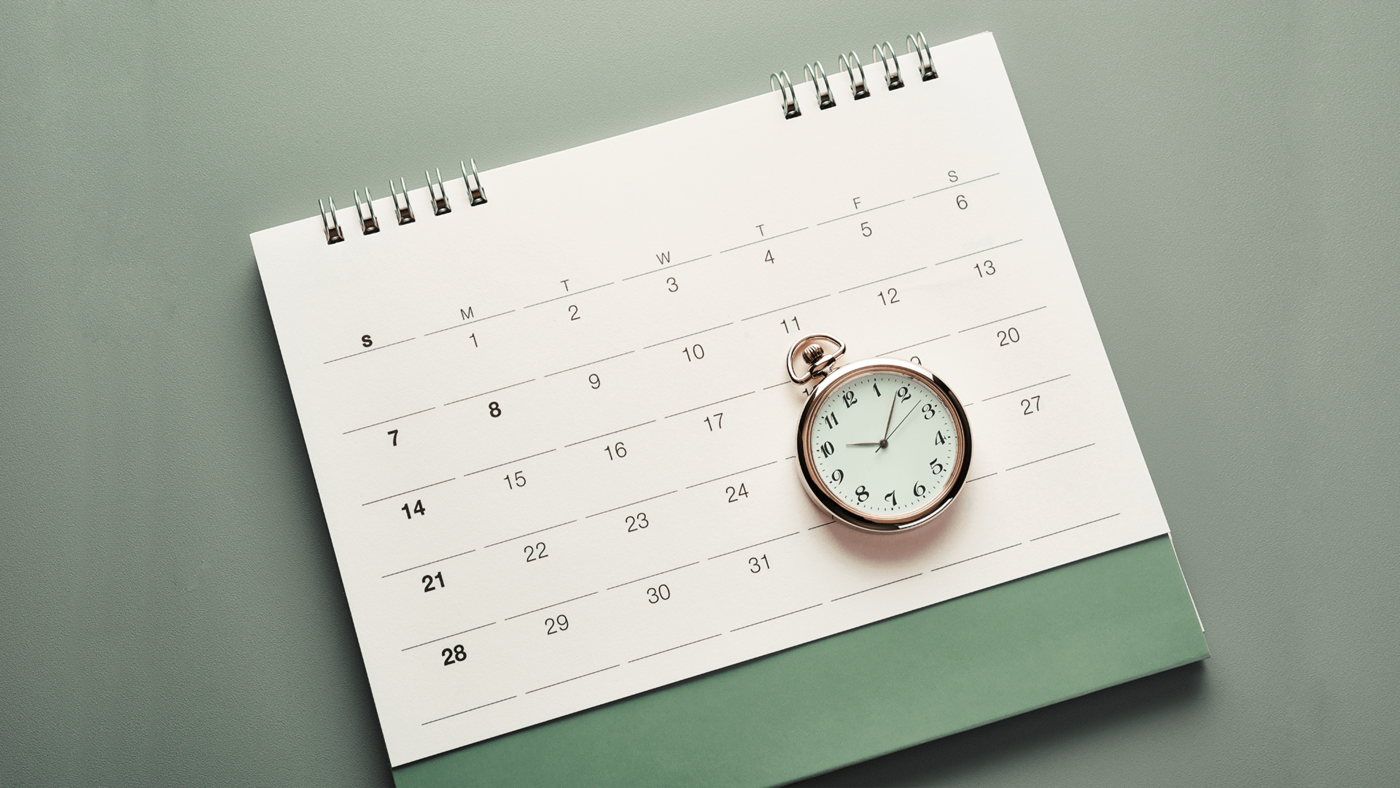 Ein grüner Terminkalender auf dem eine Taschenuhr liegt.