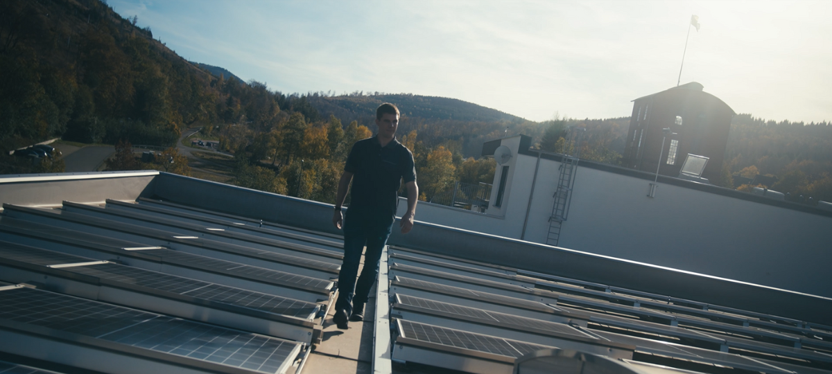 Das Bild zeigt das Dach der Condensator Dominit GmbH mit erneuerbaren Energien und einem Mitarbeiter